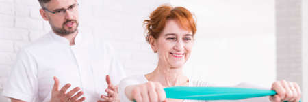 Woman exercising with a tape and professional physiotherapist, panorama