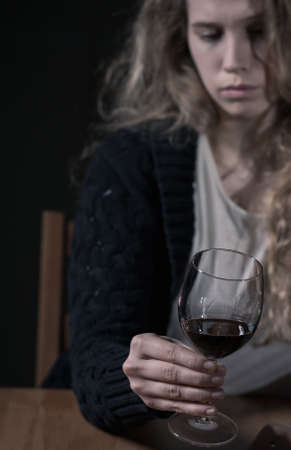 Shot of a sad young woman holding a glass of red wineの写真素材