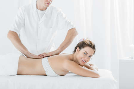 Young woman having professional massage, lying in white interiorの写真素材
