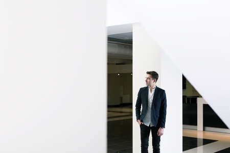 Handsome elegant young graduate in modern new spacious building of university