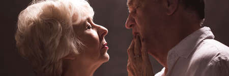 Senior woman touching softly her husband's lips with finger
