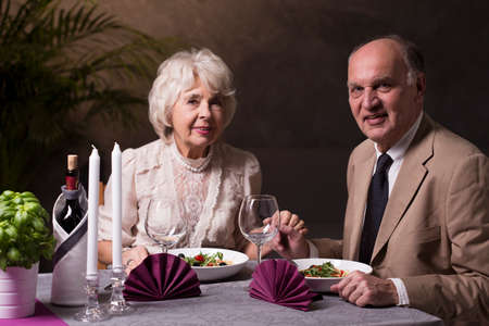 Shot of an elderly couple having a romantic dinner and looking at the cameraの写真素材