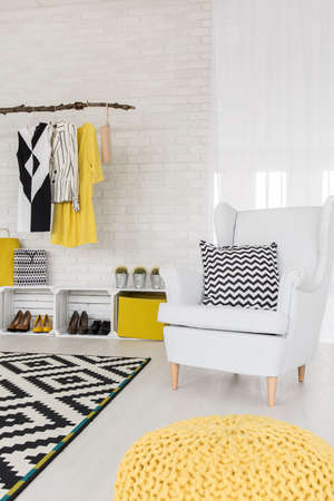 White interior with white armchair, hanging clothing rack and pattern details