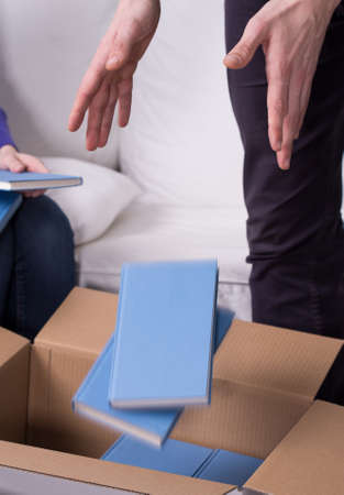 Cropped picture of a man throwing books into a box
