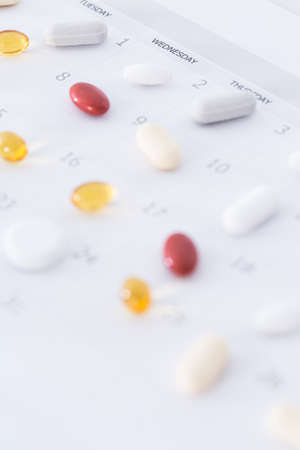 Close up of various pills lying on a white table