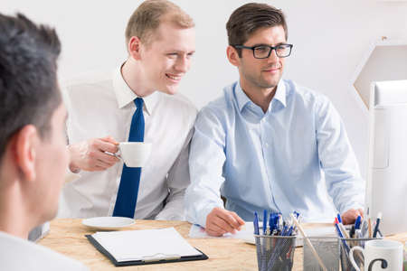 Two designers and his client during business meeting, sitting in light office