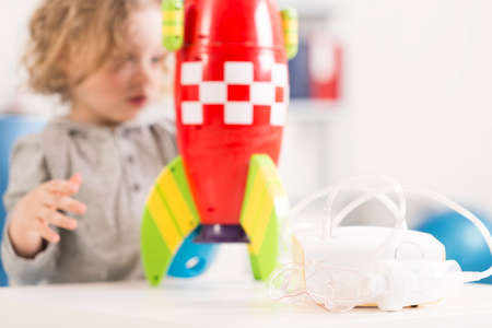 Close up of an inhaler device, blurred image of a child with a toy racket in the backgroundの写真素材