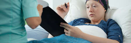 Cancer young woman signing documents in hospitalの写真素材