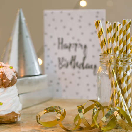 Big puffs pastry with cream, birthday paper cap, present and card on table prepared for celebrantの写真素材