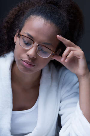 Close-up portrait of a young woman wearing glasses, concentrating on something at nightの写真素材