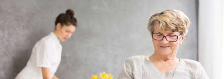 Panoramic picture od a senior woman and her caregiver standing in the backgroundの写真素材