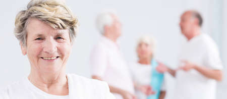 Panoramic picture of a smiling senior woman and her friends talking in the backgroundの写真素材