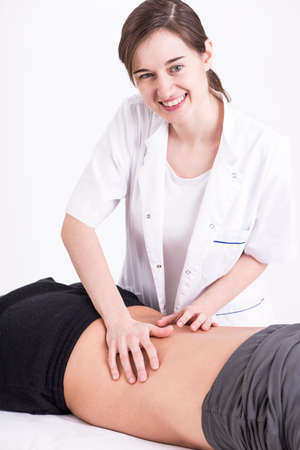 Young physical therapist giving a back massage to a man on a massage tableの写真素材