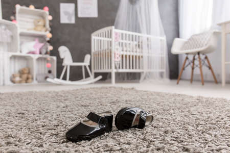 Shot of black baby shoes laying on a carpet in a nursery