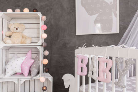 Shot of a crib and some boxes in a grey and white baby room