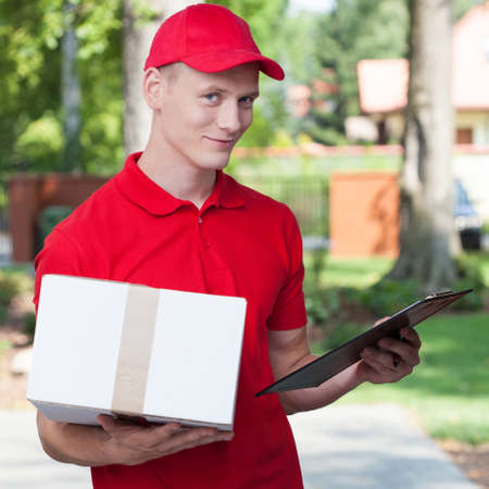 Delivery man holding a package and a clipboardの写真素材