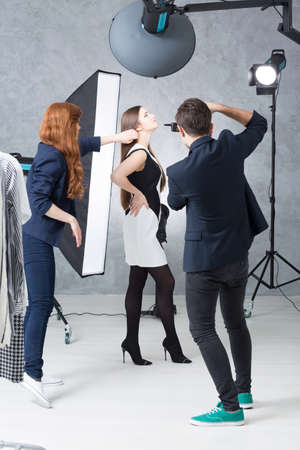 Fashion session in a photographic studio, with a model in a black and white dress, a photographer...