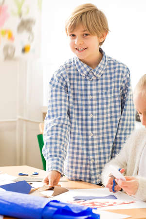 Smiling little boy having fun during art classes. Sitting next to his friend and drawing the pictureの写真素材