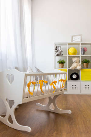 Shot of a crib in a modern white and yellow baby room