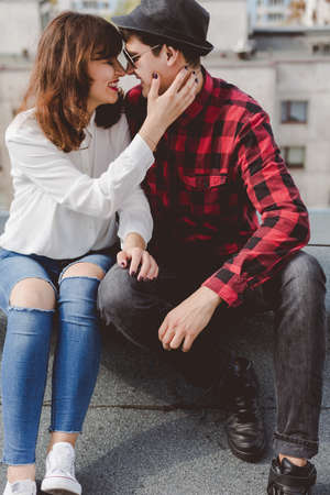 Young couple is tenderly hugging and sitting on a rooftop