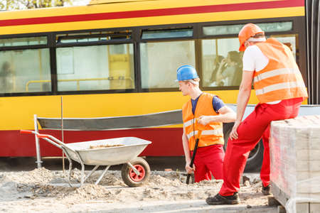 Road construction workers with a city bus in the backgroundの写真素材