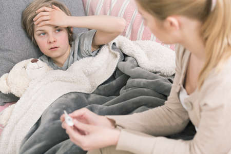 Shot of a young woman checking her son's temperatureの写真素材