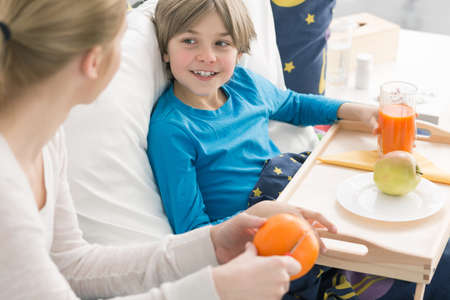 Shot of a happy little boy laying on a bed and smiling to his mumの写真素材