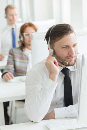 Call center worker sitting beside desk in light officeの写真素材