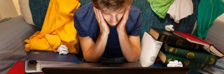 Top view of exhausted student sitting on the couch with laptop