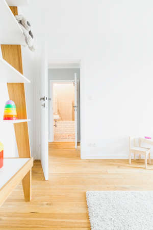 Spacious and light child room with hardwood flooring and simple furnitureの写真素材