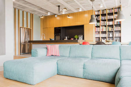 Spacious living room with a large light sofa, open kitchen area in the backgroundの写真素材