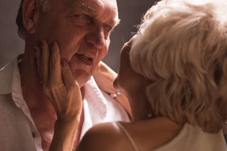 Mature man looking at his senior wife, dark bakgroundの写真素材