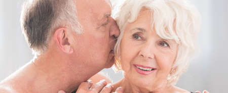 Older man tenderly and gently kissing his wife on the cheekの写真素材