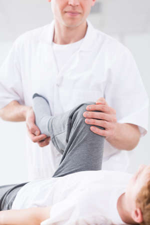 Physiotherapist deals with the leg of a boyの写真素材