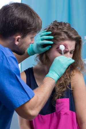 Shot of a young doctor cleaning a wound on a young woman's headの写真素材