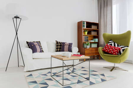 Room corner of a modern flat, with a designer swivel armchair and a modernist bookcase