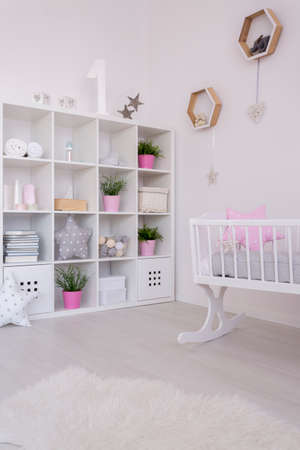 Delicate baby room's decor with soft decorations and a fur rug on the white floorの写真素材