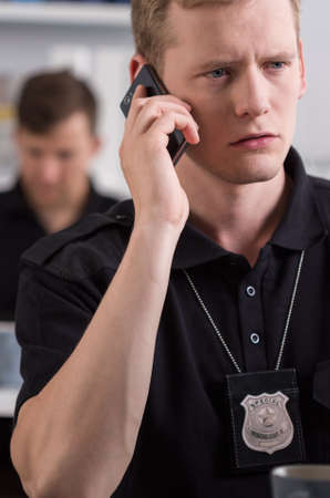 Young police officer with a badge talking on a cellphoneの写真素材