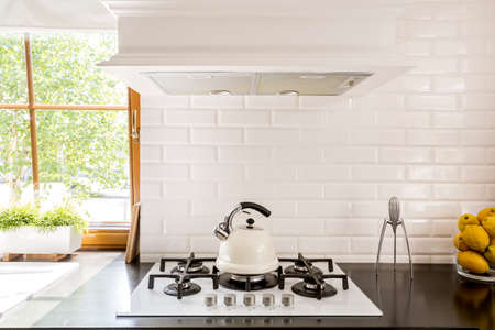 New style kitchen with dark worktop, white gas cooker and decorative brick backsplash
