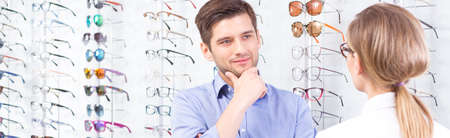 Shot of a young man standing against a wall full of glasses