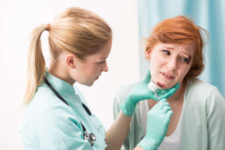 Shot of a doctor cleaning a wound on a young woman's face