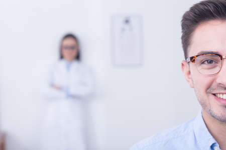 Handsome young smiling man in a new glasses in optician's storeの写真素材