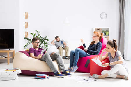 Group of students learning together in a modern apartment, sitting on colorful bean bagsの写真素材