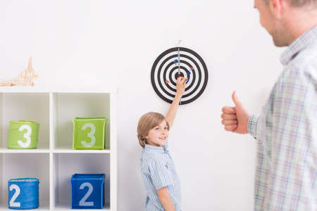Father and son playing darts at light home interiorの写真素材