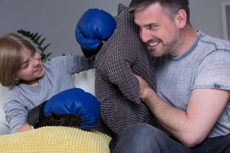 Happy father and son sitting on a sofa and playing together