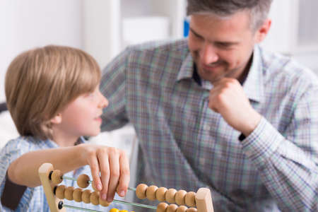 Happy father and son, small boy counting with abacusの写真素材