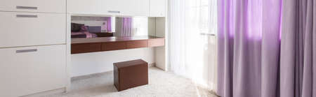 Stylish bedroom with white furniture, carpet and decorative purple curtainsの写真素材