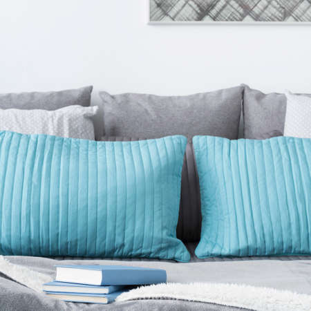 Photo of decorative turquoise and grey cushions on bedの写真素材