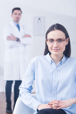 Smart young woman in optician store looking for a new glasses. Trying thin brown glass frameの写真素材