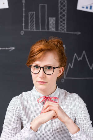 Serious woman wearing eyeglasses, in the background blackboardの写真素材